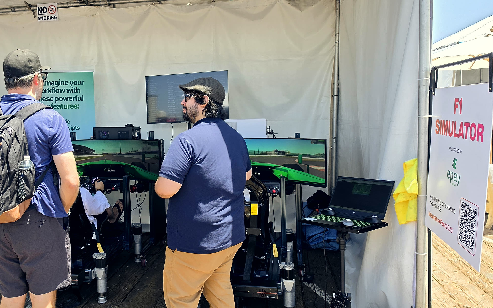 Trackside full-motion Formula 4 simulators in the Epay Policy tent at Insurance Fest 2026 on the Santa Monica Pier