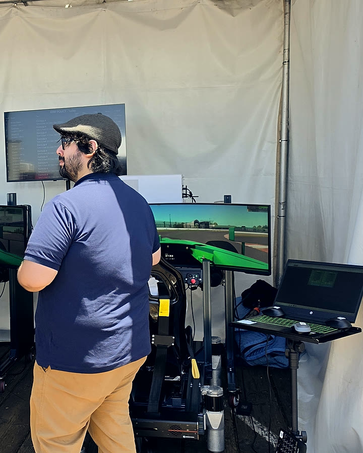 Attendees watching a driver mid-session in the Epay Policy formula racing tent at Insurance Fest