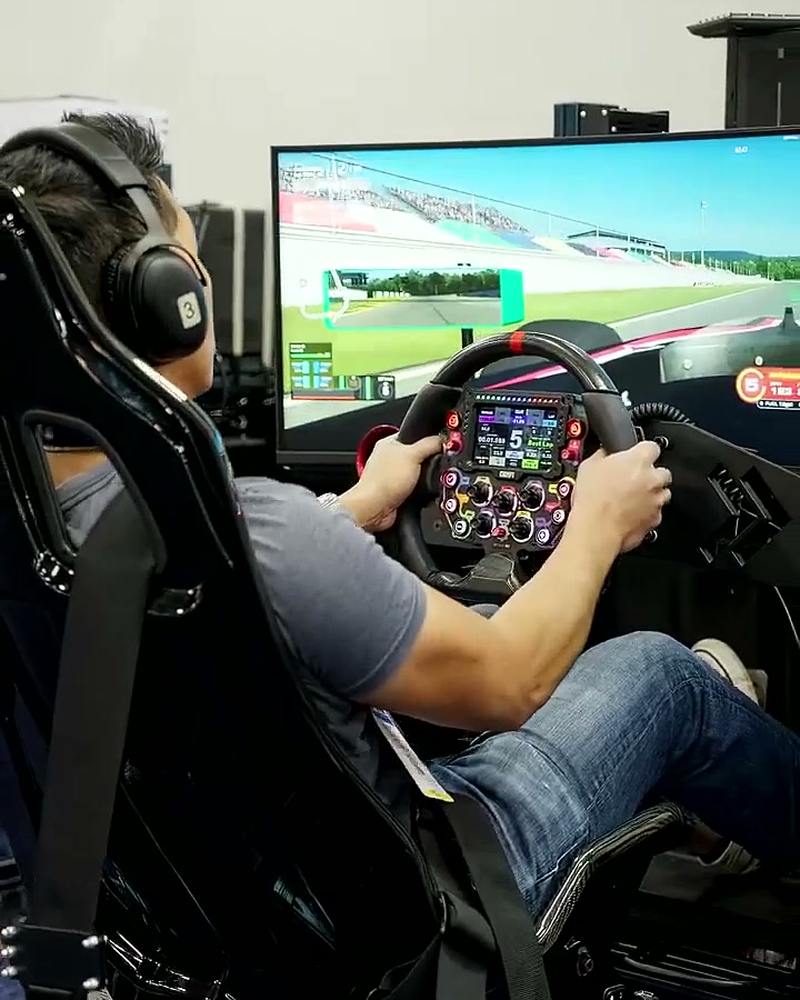 A driver mid-race with the track live on the big screen