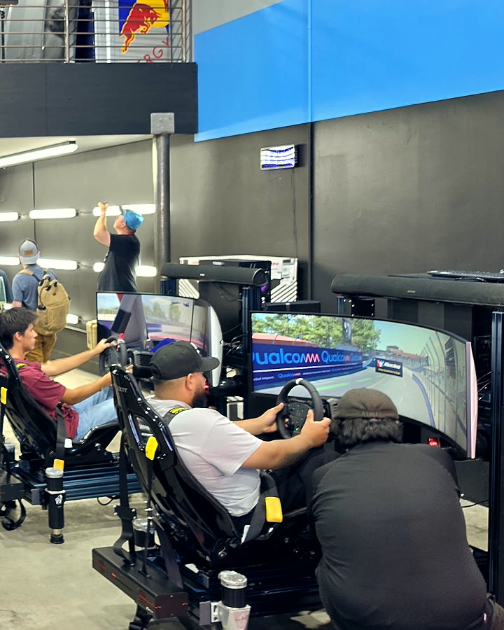 Two fans racing head-to-head on networked full-motion simulators at the NASCAR San Diego activation
