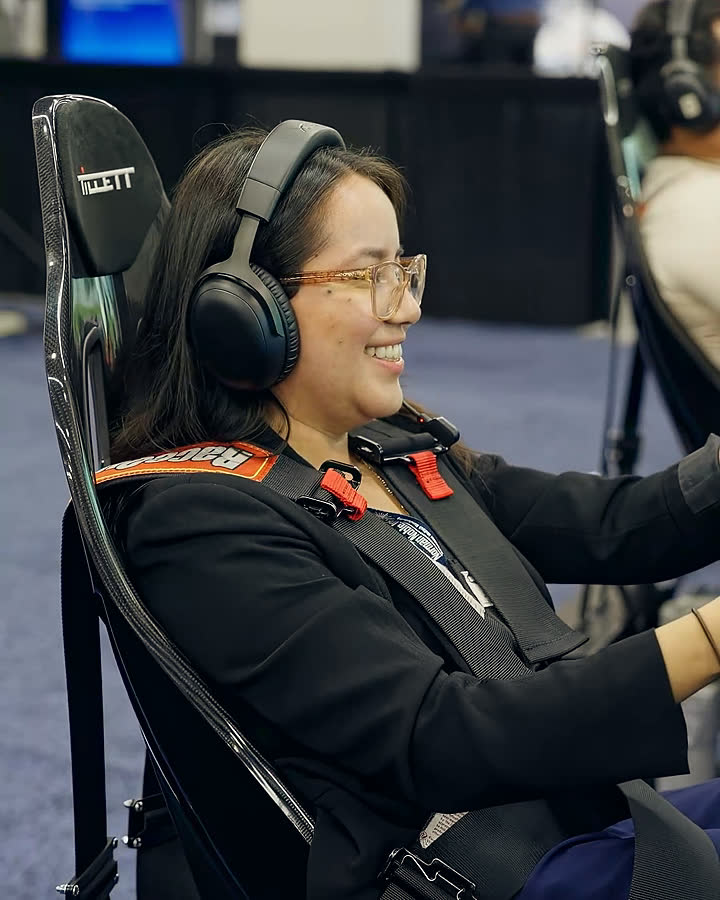 A smiling guest in a racing headset mid-session at a trade-show activation